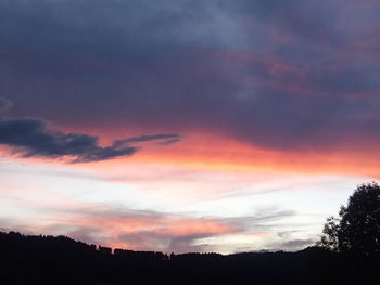 Low angle view of silhouette trees against dramatic sky