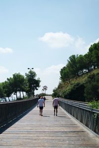 Rear view of people walking on footbridge