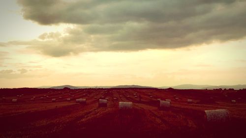 Hay bales on field against sky during sunset