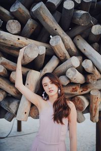 Portrait of young woman standing on wooden logs