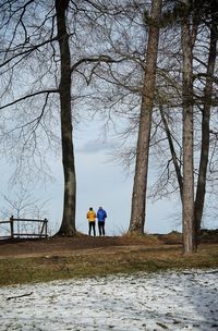 Rear view of men on field against sky