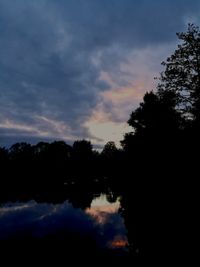 Reflection of silhouette trees in calm lake