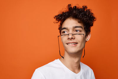 Portrait of smiling young man against orange background