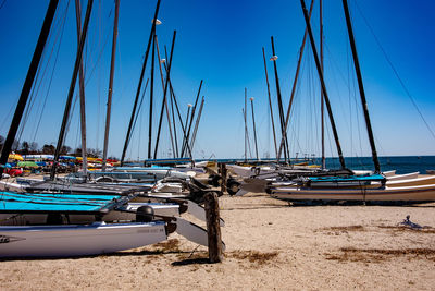 Sailboats moored in sea against clear blue sky