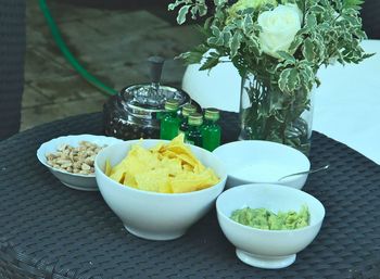 High angle view of guacamole served with tortilla chips and peanuts in bowl on table