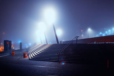 Illuminated city street against sky at night