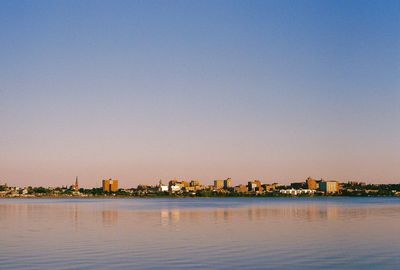 Buildings by sea against clear blue sky