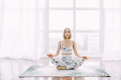 Short-haired girl does exercises, physical exercises, yoga and stretches on a rug against at home