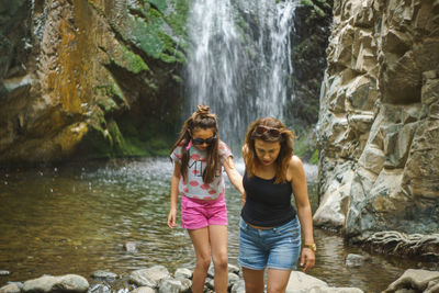 Full length of girl standing on rock by river