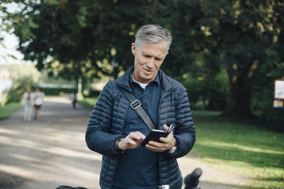 Senior man using mobile phone while standing in park