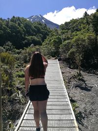 Rear view of woman standing on umbrella against sky