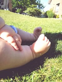 Low section of baby sitting on lawn