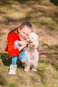 Portrait of girl with dog crouching at park