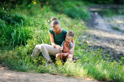 . mom hugs boy, helps him. concept of happy childhood in nature and happy single parent