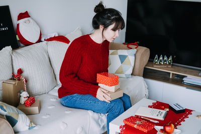 Side view of woman sitting on sofa at home