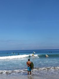 Rear view of man on beach against sky
