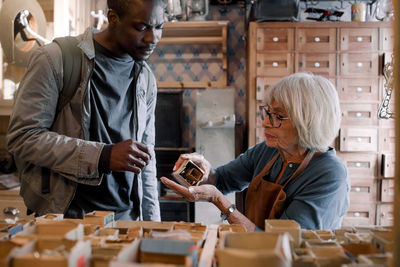 Senior saleswoman assisting male customer with nails at hardware store