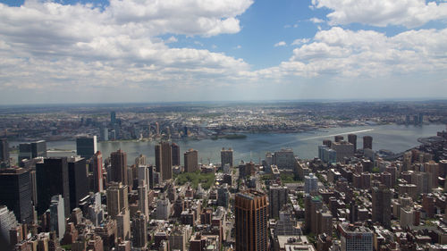 Aerial view of city by sea against sky