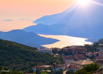 Scenic view of townscape and mountains against sky at sunset