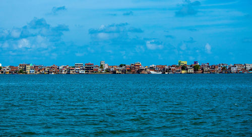 Sea by buildings against blue sky