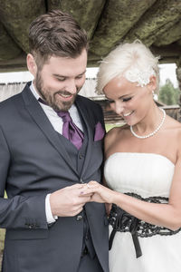 Smiling bride and groom looking at wedding ring