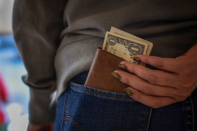 Midsection of woman removing wallet from jeans