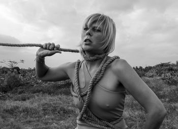 Midsection of woman holding camera on field against sky