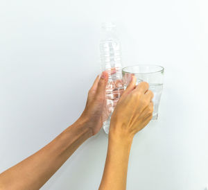 Midsection of woman drinking glass against white background