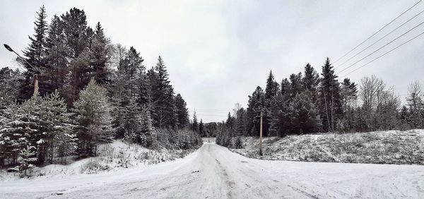 Panoramic view of snow covered road against sky