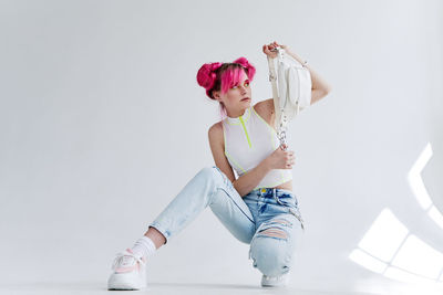 Portrait of smiling young woman with arms crossed against white background