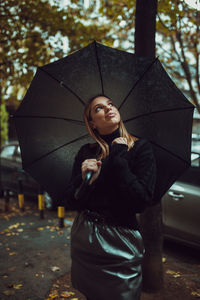 Midsection of woman with umbrella standing in rain