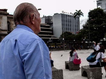 Rear view of men on sidewalk in city against sky