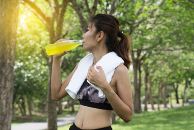 Mid adult woman drinking energy drink in park