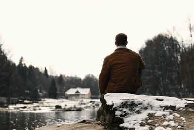 Rear view of man looking at lake against sky