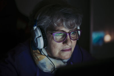 Close-up of senior teacher wearing eyeglasses while working over laptop at home