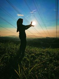 Silhouette man standing on field against sky during sunset