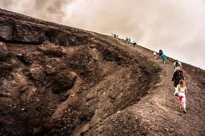 Rear view of people walking on landscape against sky