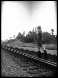 Man standing on railroad tracks against clear sky