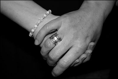 Cropped hands of couple against black background