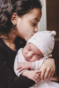 Cute girl kissing on brother head at home