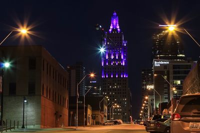 Illuminated street amidst buildings in city at night