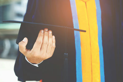 Midsection of woman holding mortarboard