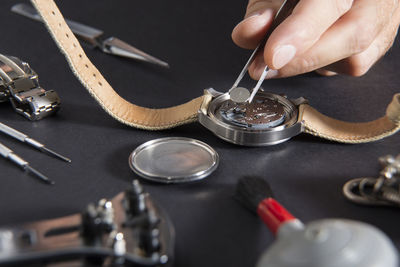 Cropped hand of craftsperson repairing wristwatch at desk