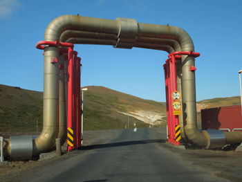 Road by factory against clear blue sky