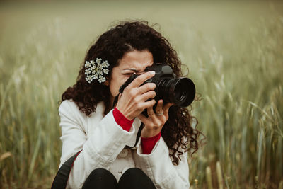Woman photographing through camera on field