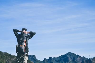 Rear view of man standing against mountains and sky