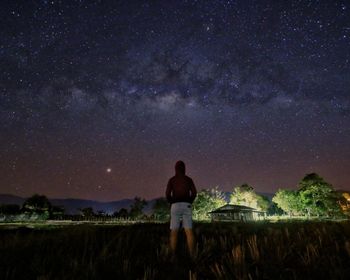 Rear view of man standing on field against sky