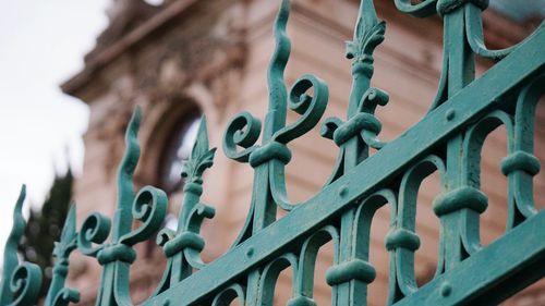 Close-up of metallic fence against historic building