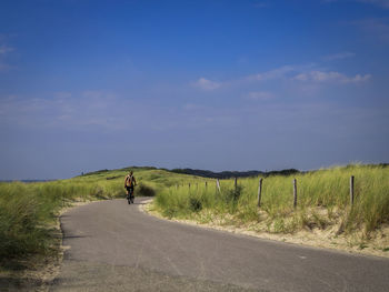 Rear view of woman walking on road against sky