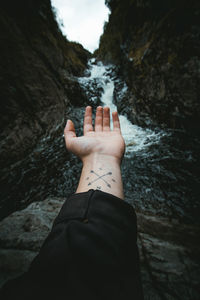 Cropped image of hand against waterfall